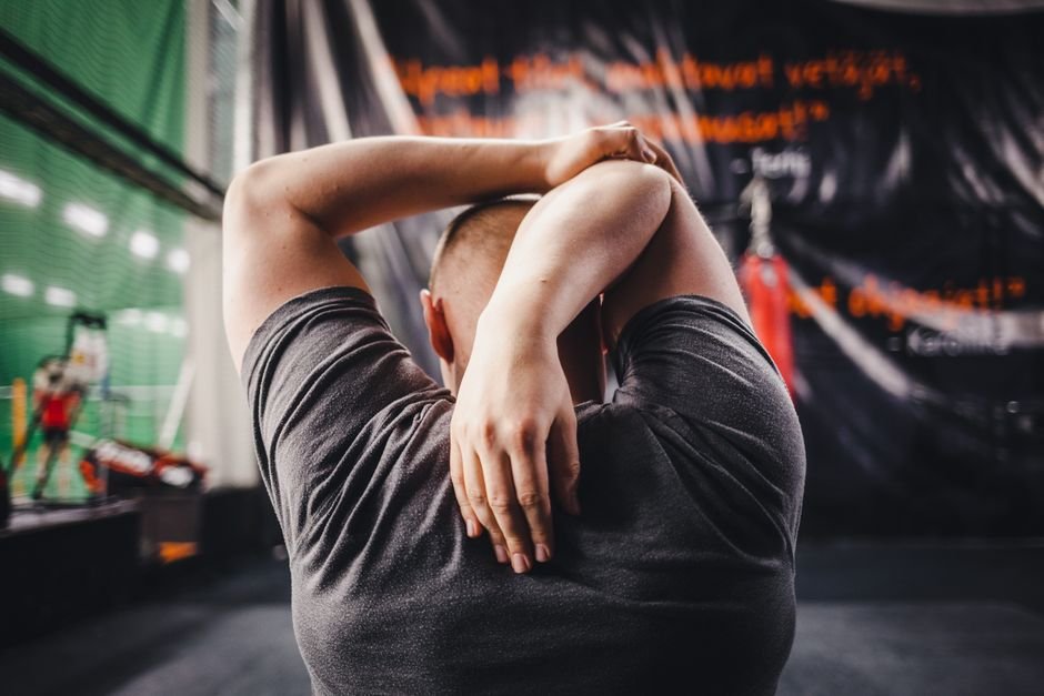 Spor salonunda kollarını esneterek egzersiz yapan erkek
