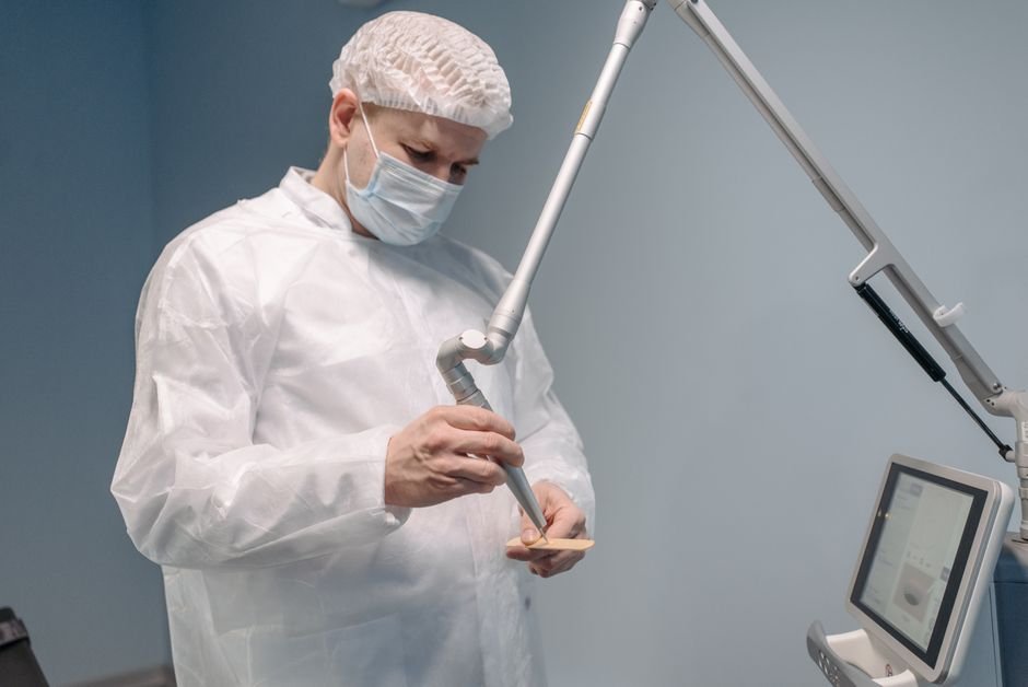 Klinikte lazer cihazını hazırlayan koruyucu giysili hekim